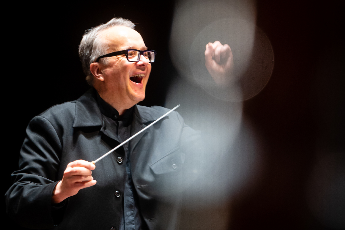 Music Director of Orchestra Wellington, Marc Taddei, smiling on the podium mid-performance